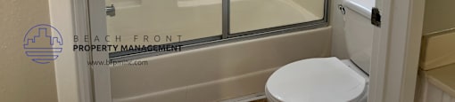 A white toilet is in a bathroom with a walk-in shower.